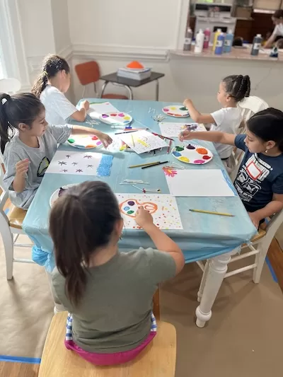 5 children around a table painting