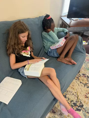 Two young girls on a couch reading