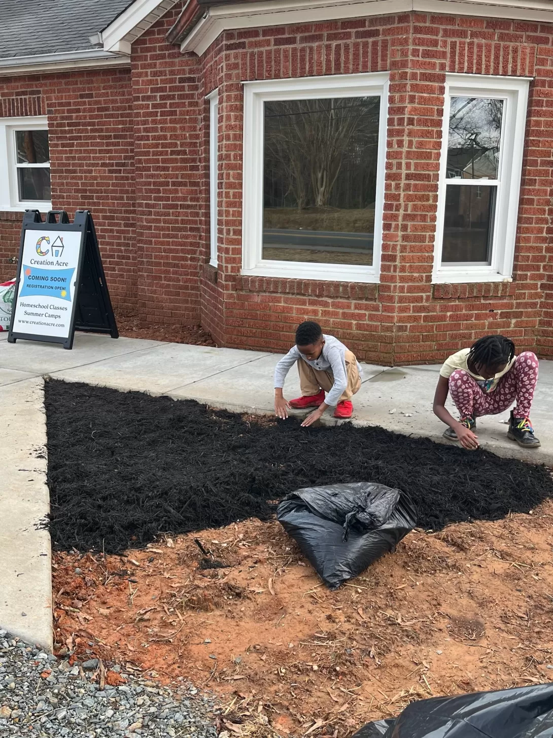 Kids adding mulch to front entrance